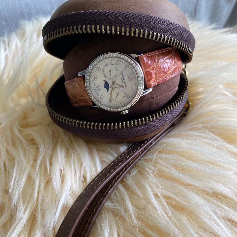 Opened donut-shaped leather watch case that shows a ladies watch inside.